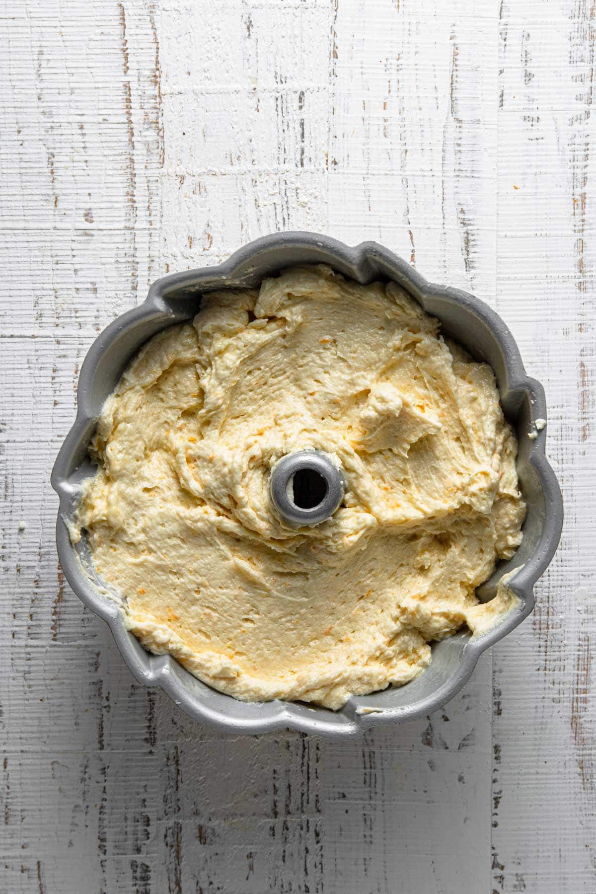A bundt pan with raw orange pound cake batter.