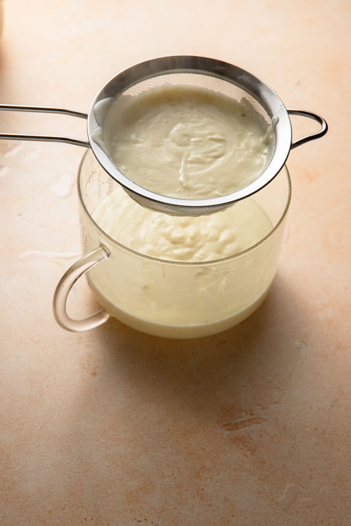 Running Budino through a sieve into a large bowl.