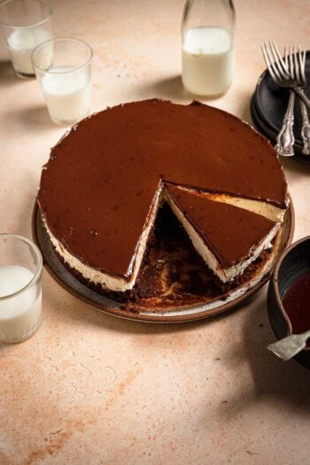 Crembo cake with cups of milk, plates and forks next to it.