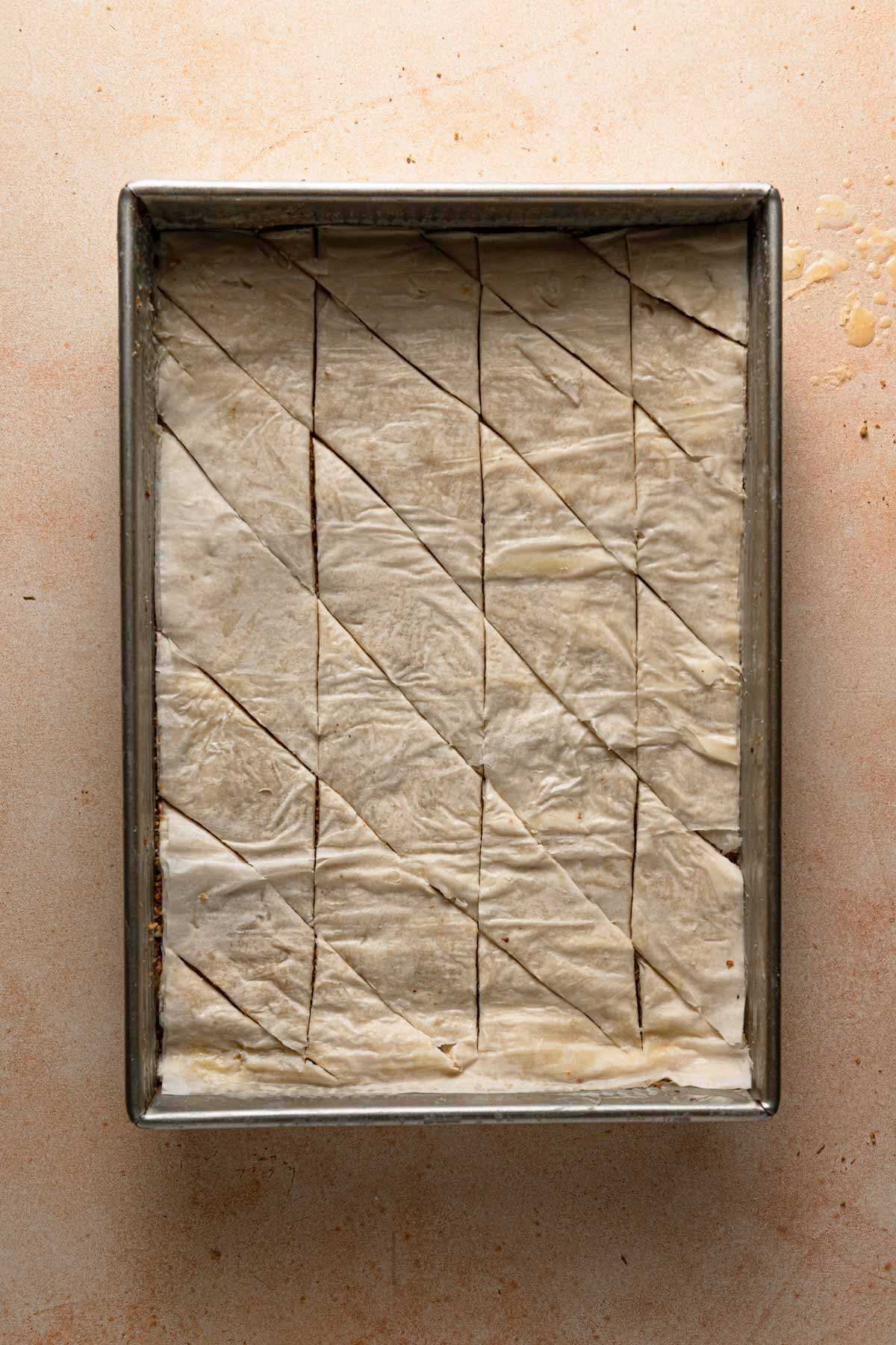 Un baked Baklava partly sliced.