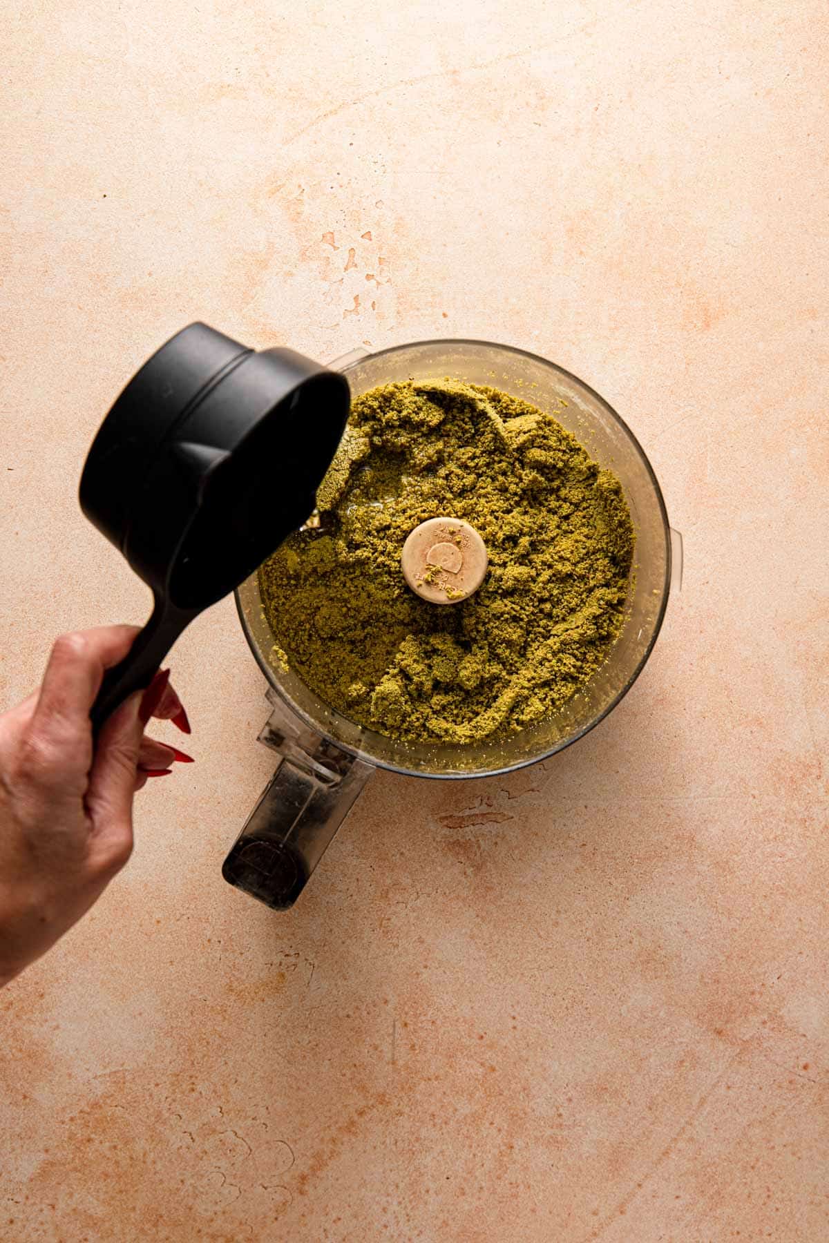 Adding oil to a food processor with nut powder.