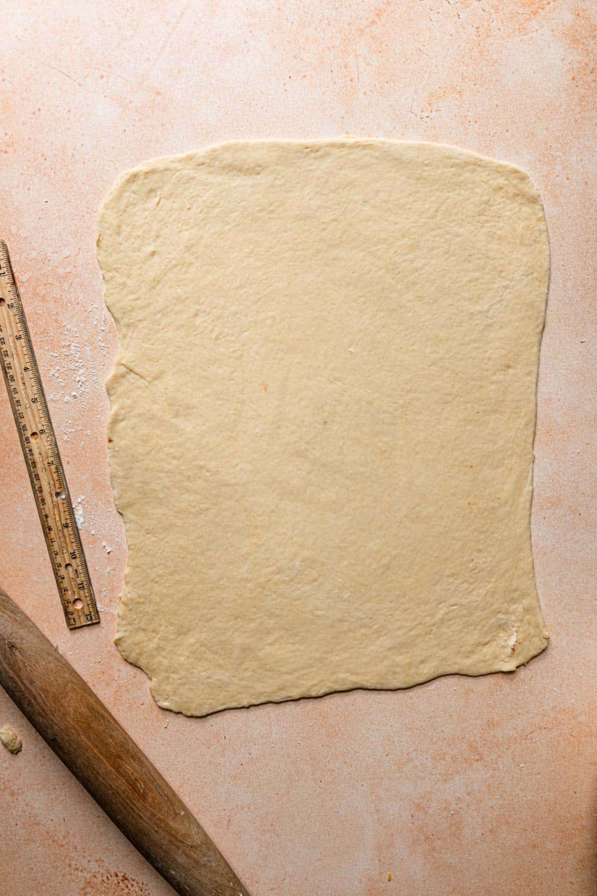 a dough rectangle next to a ruller or a rolling pin.