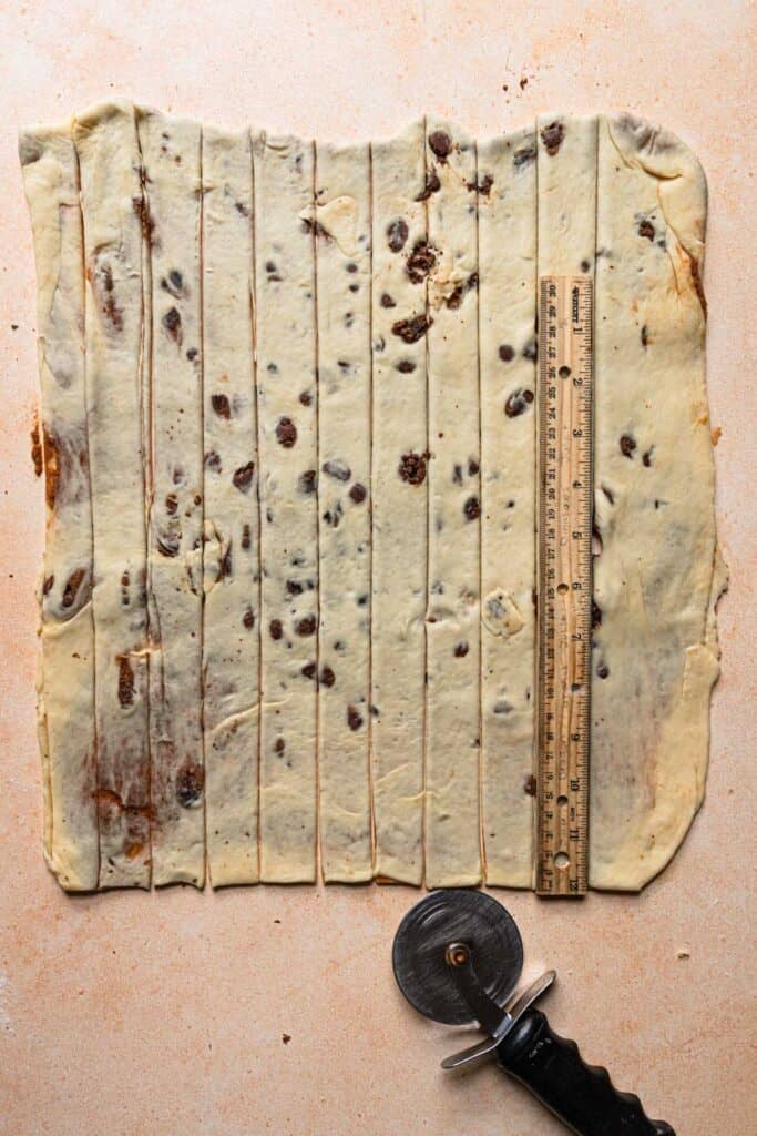 Sliced dough next to a pizza wheel and a ruller.