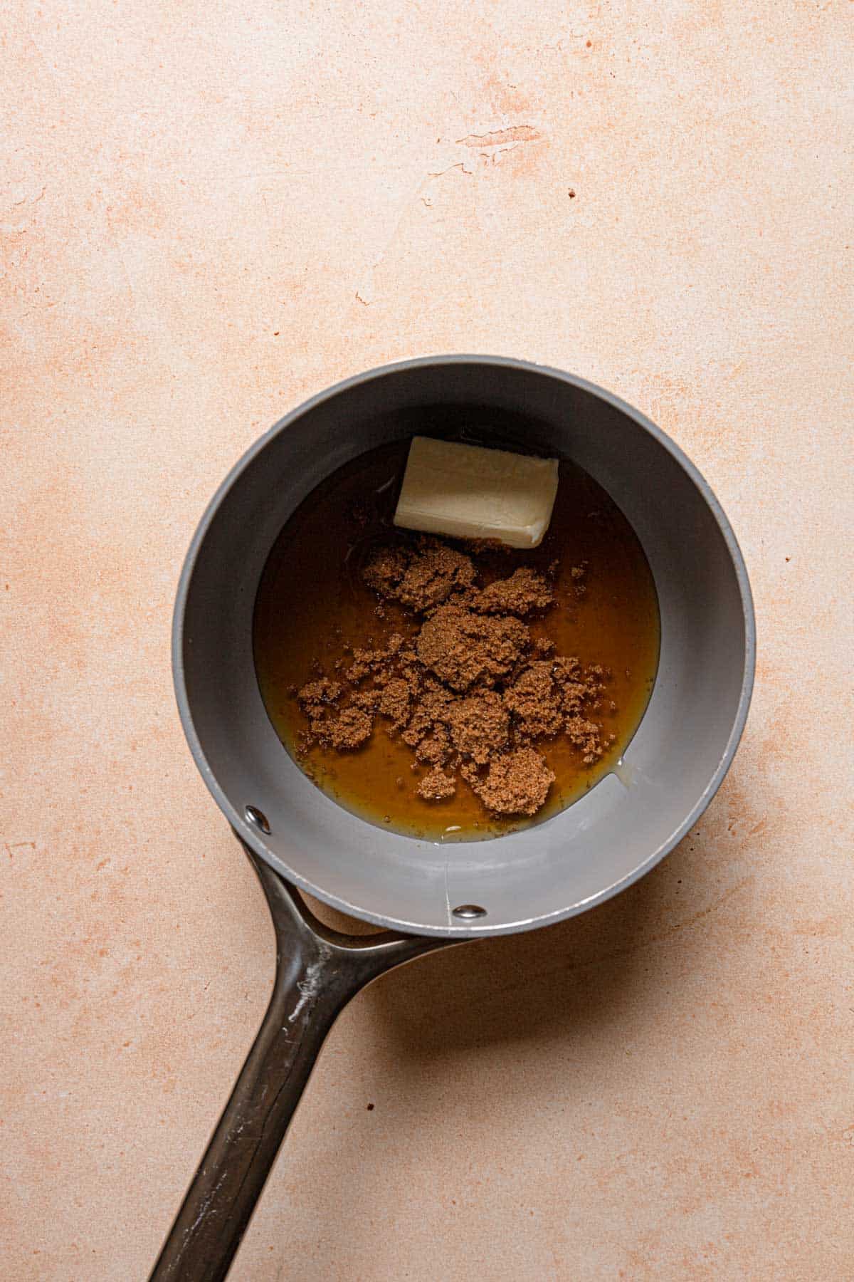 A saucepan with butter, honey and brown sugar.