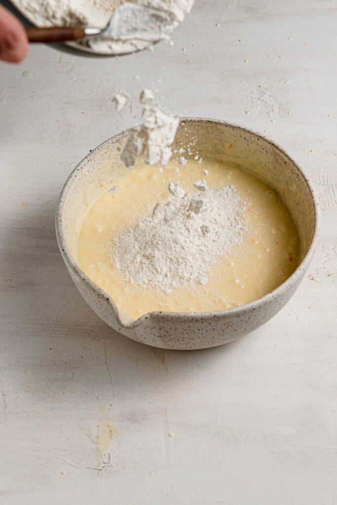 Adding flour to cake batter.