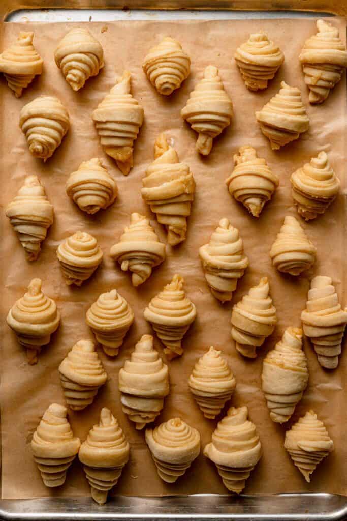 Unbaked israeli style almond rugelach in a pan lined with parchment paper.