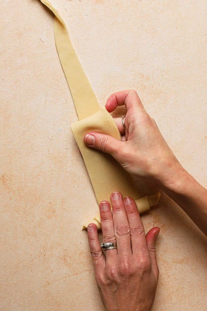 hands rolling dough into a crescent shape.