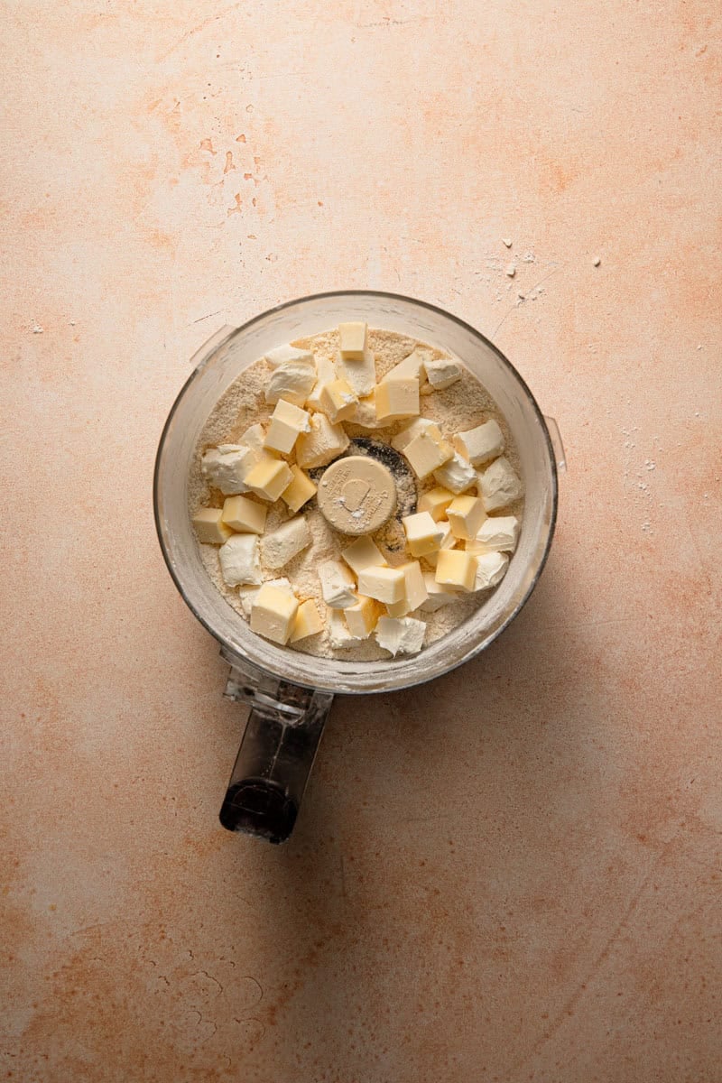 Food processor dough with flour, butter pieces, and cream cheese pieces.