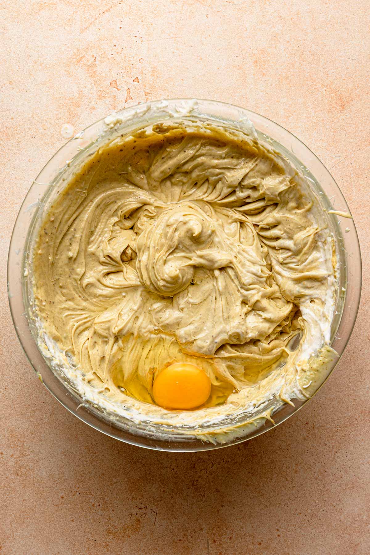 A bowl with pistachio and cream cheese mixture and an egg.