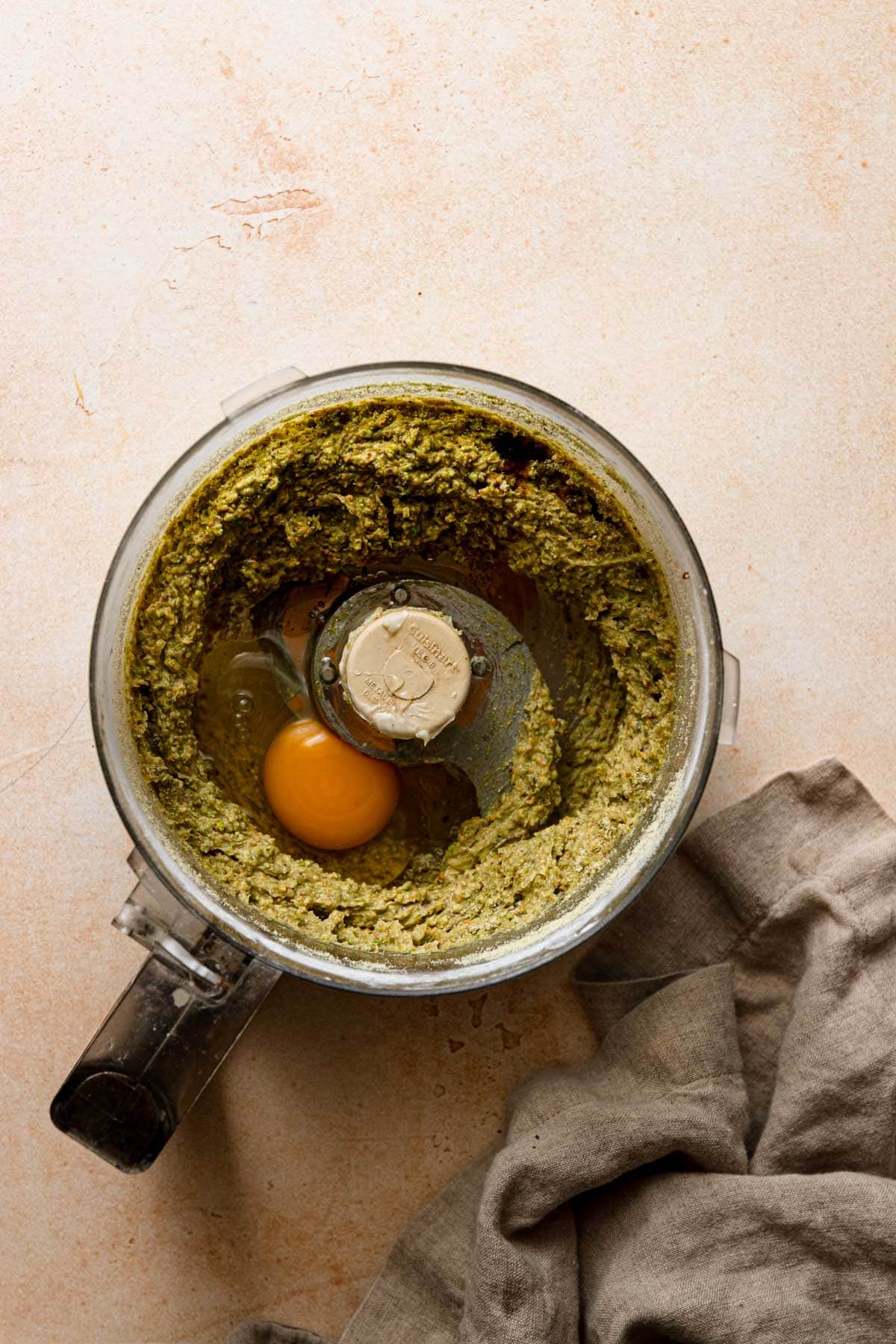 A bowl of a food processor processed cream and an egg. A napkin next to it.