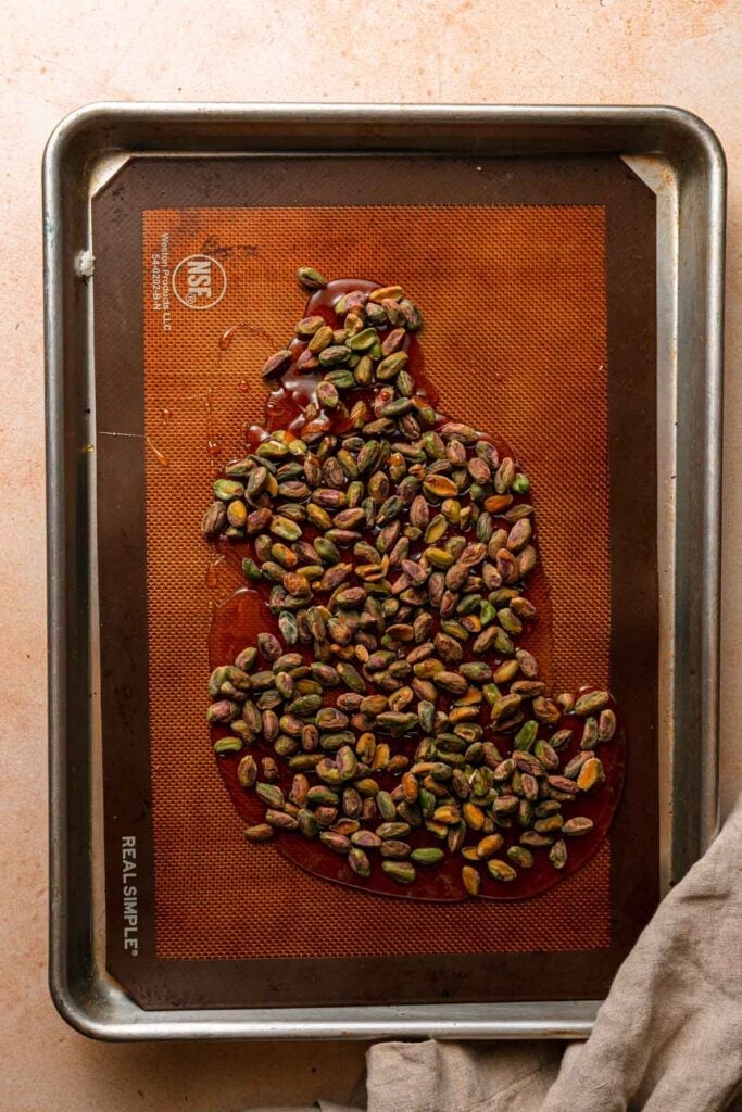 A baking pan with caramelized sugar topped with pistachios.
