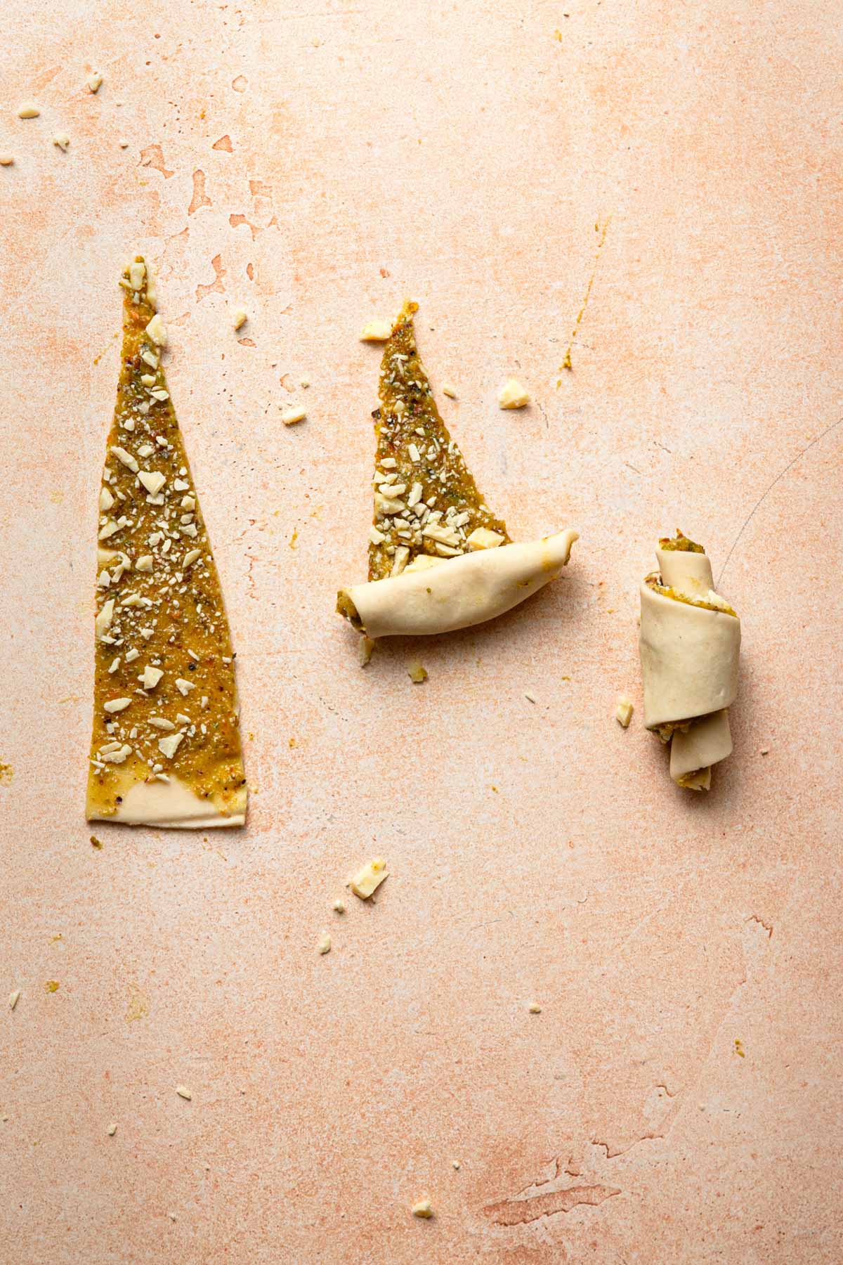 A triangle rolled dough, next to half triangle rolled dough, and a rolled crescent rugelach.