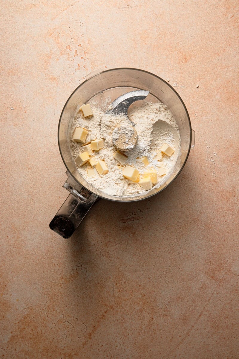 A food processor bowl with flour and butter chunks.