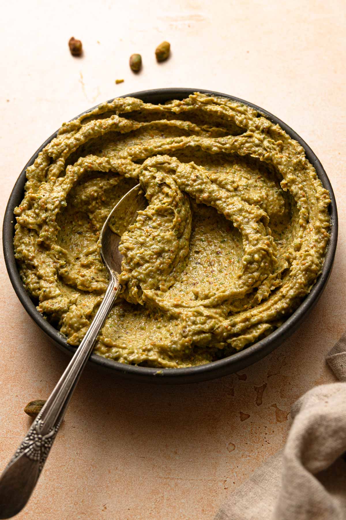 A bowl filled with pistachio frangipane with a spoon.