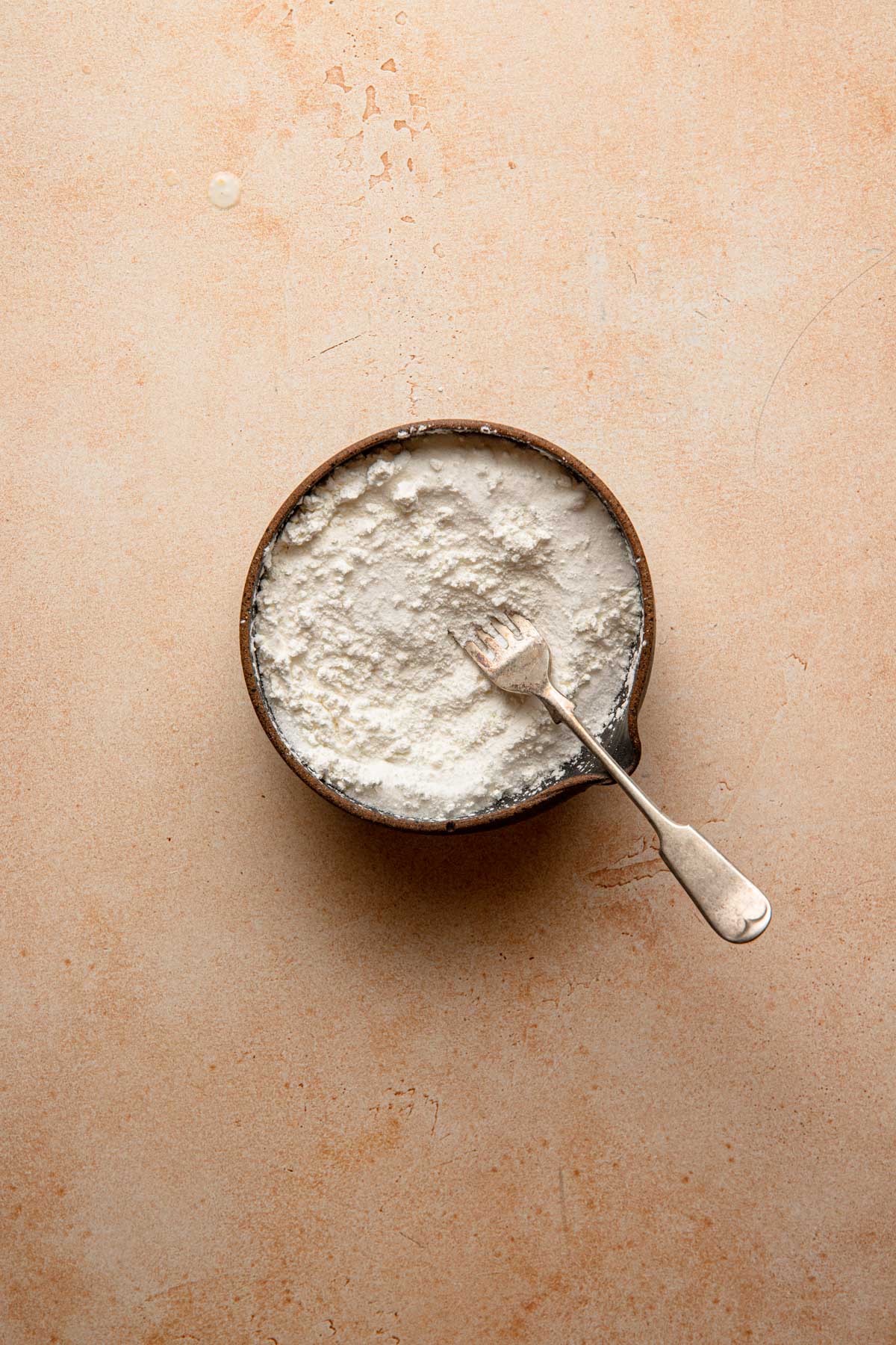 A bowl with sugar and cornstarch mixed by a fork.