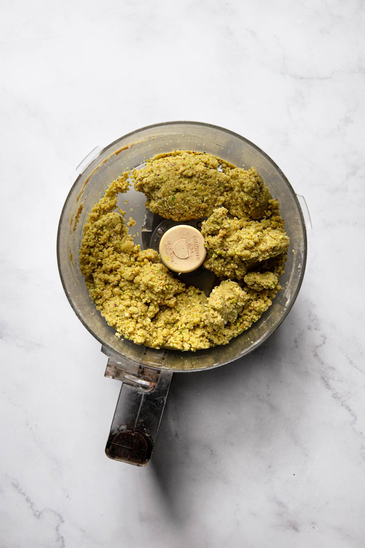 A food processor bowl with pistachio crust dough.