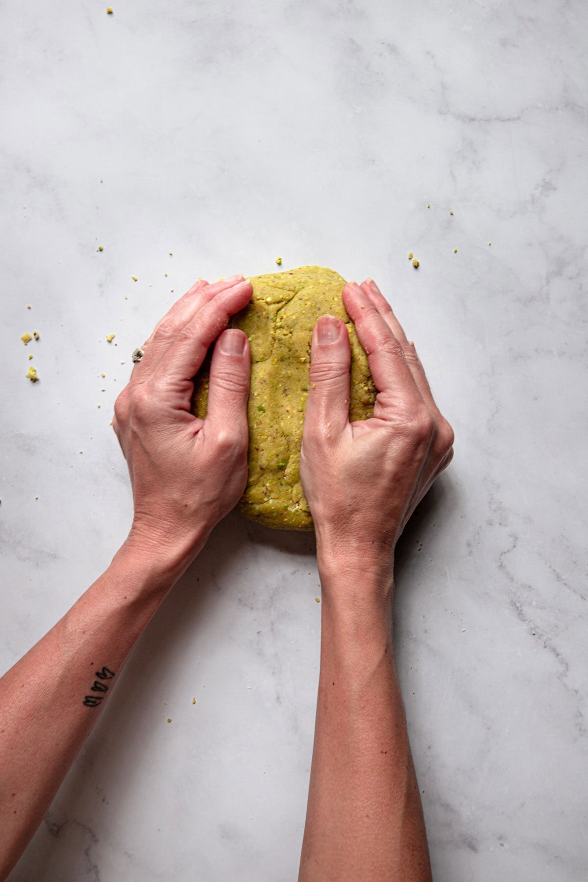 Hands pressing pistachio dough.