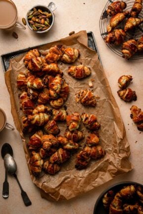 Pistachio rugelach cookies next to coffee cups.