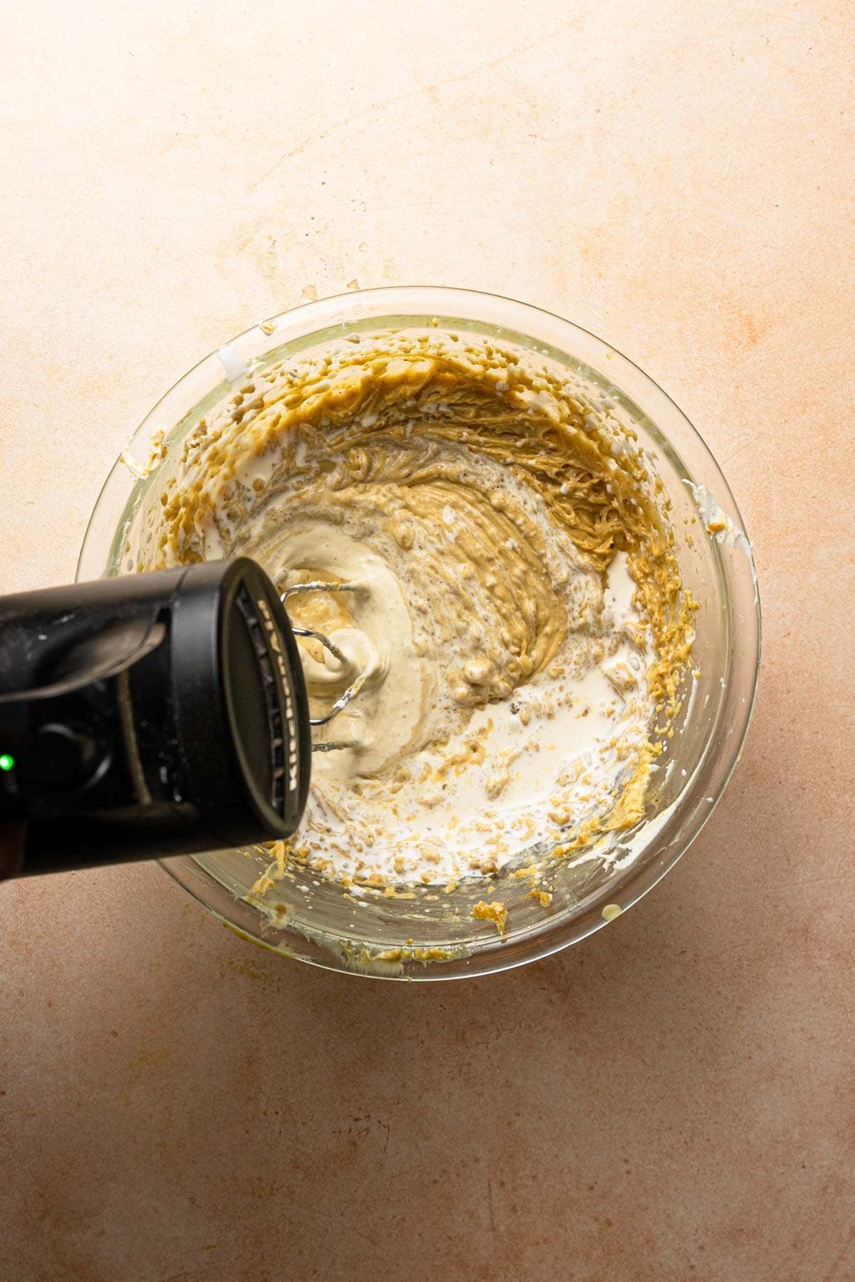 A hand mixer whisking cream into mascarpone cream.