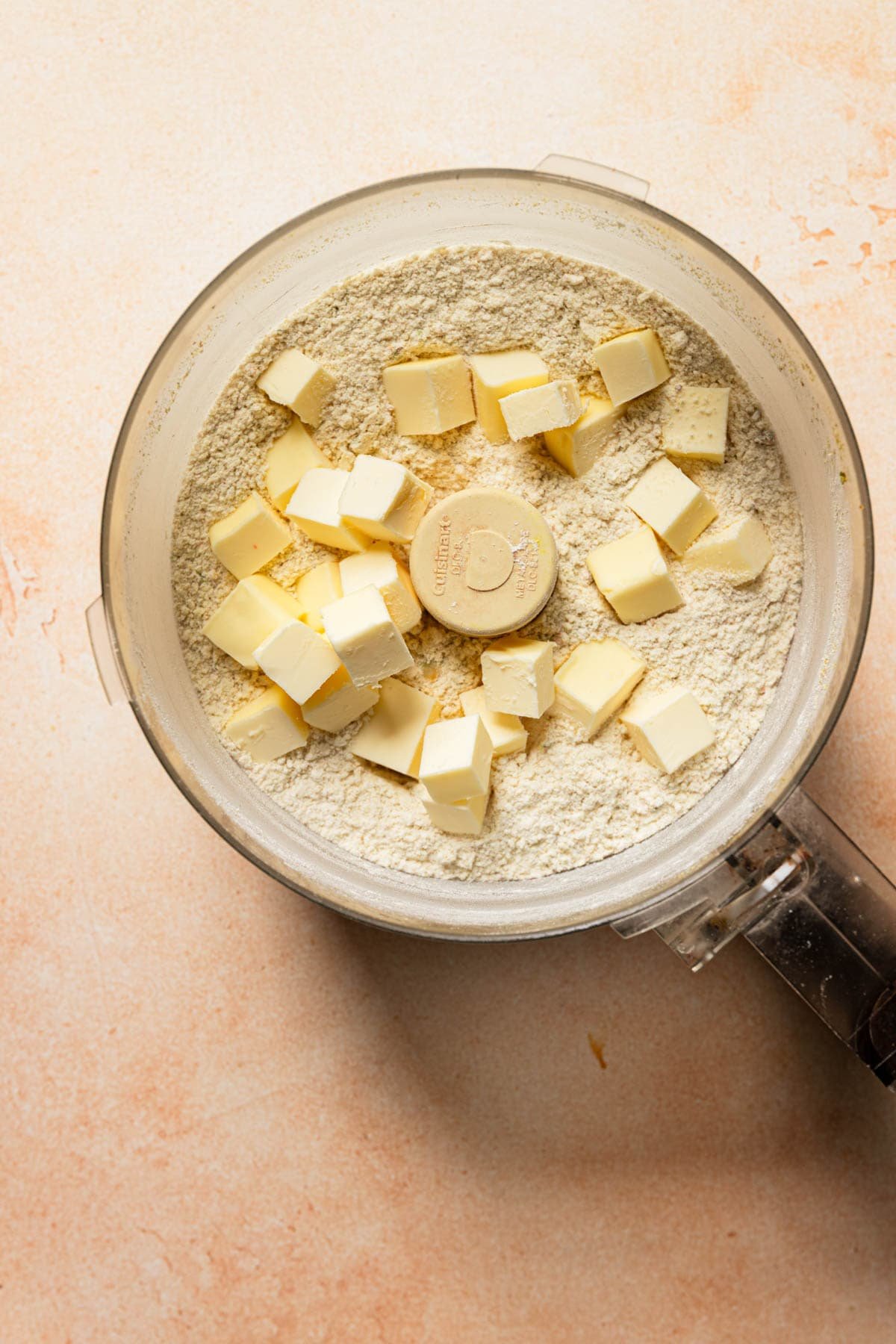 a food processor bowl with flour and butter.