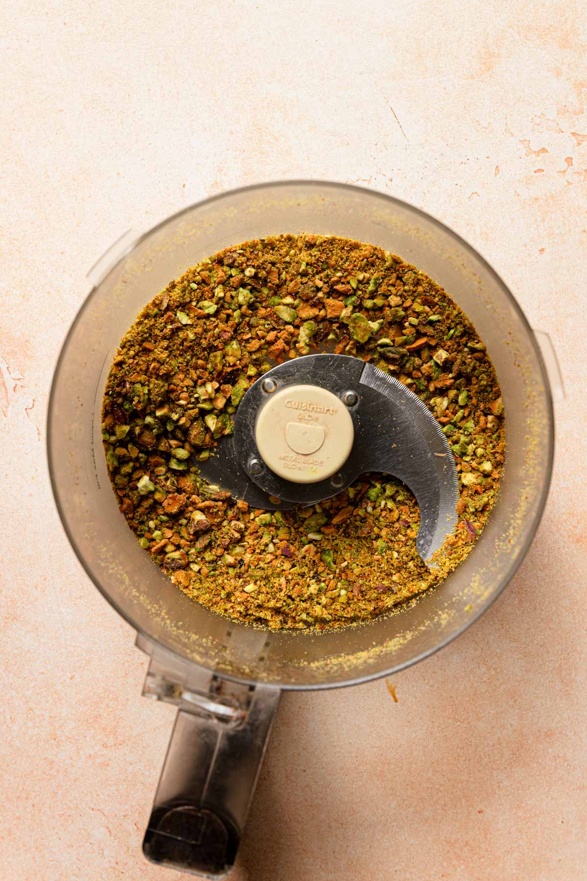 a food processor bowl with ground pistachios.