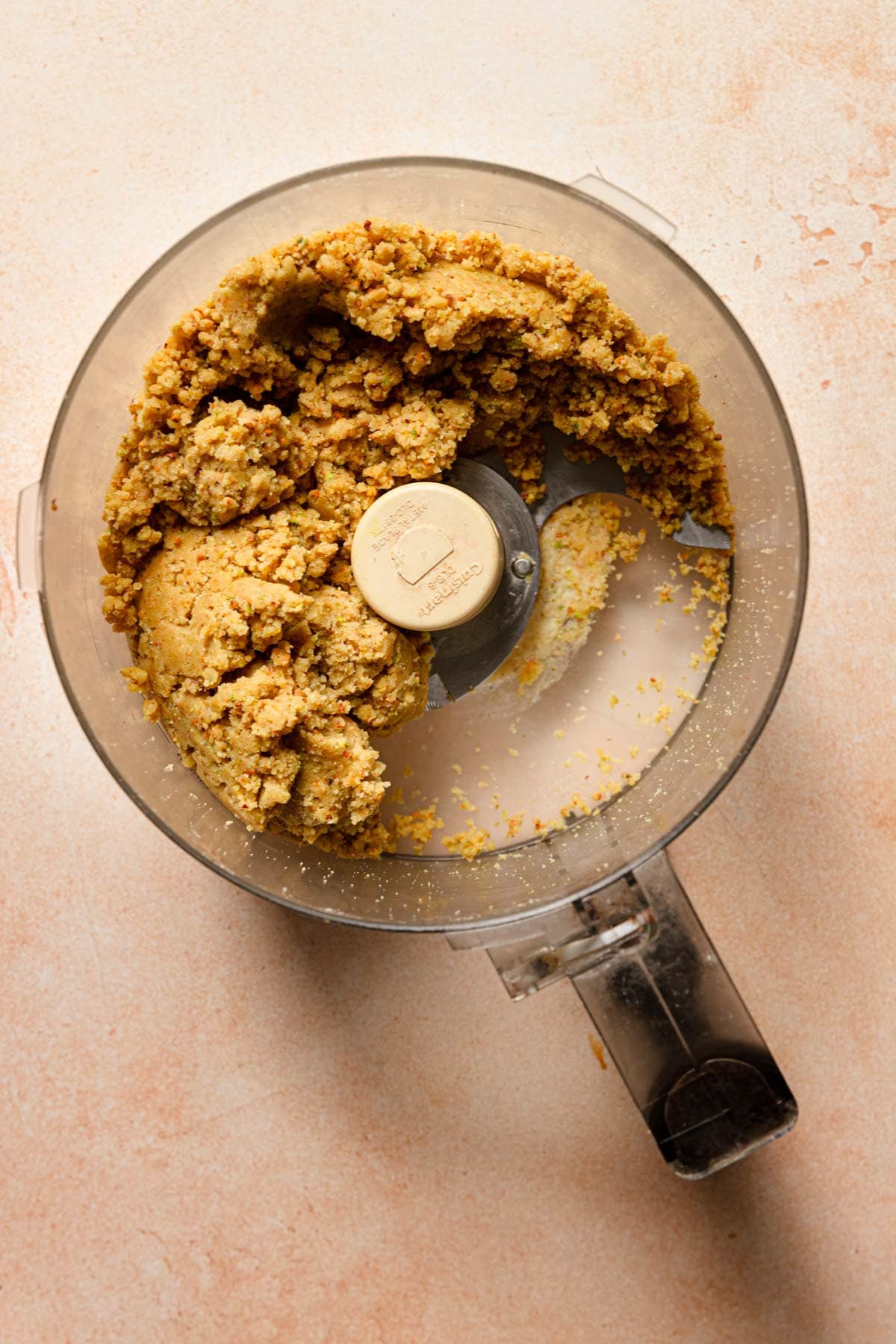 A food processor with pistachio dough for cookies.