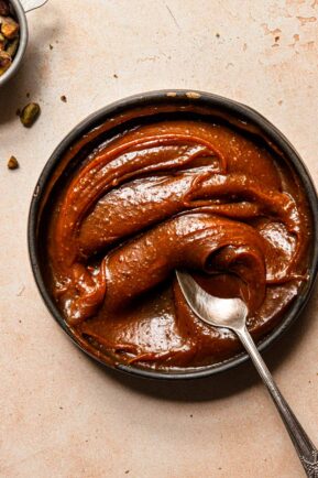 A bowl filled with caramel and a spoon.
