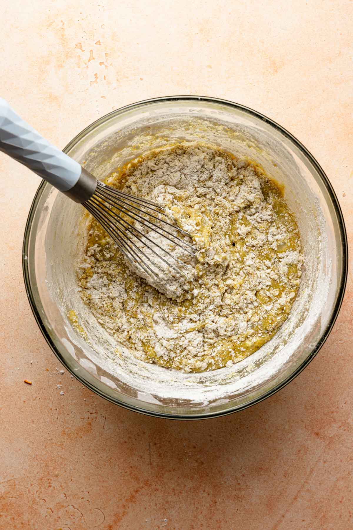 A large bowl with pistachio cake batter and a whisk.
