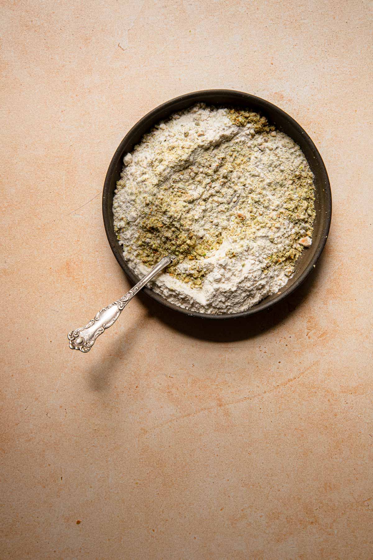 Flour and ground pistachios in a bowl with a fork.