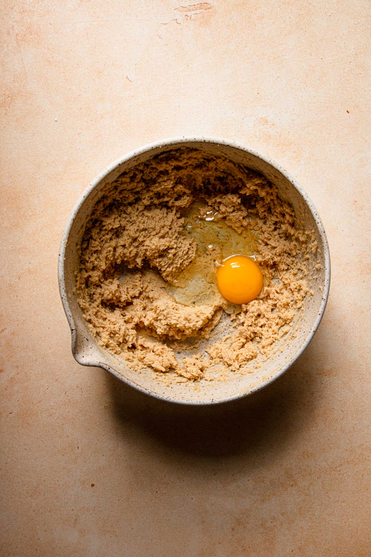 A mixing bowl with cream butter and an egg.