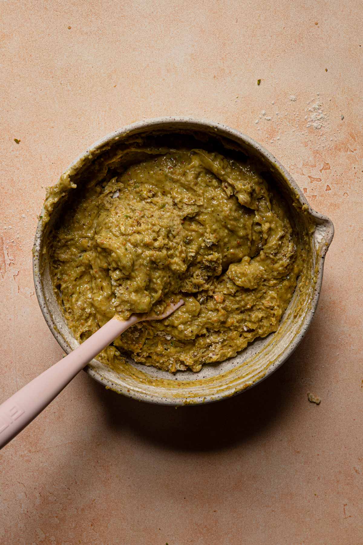 Pistachio bread batter in a bowl with a spatula.