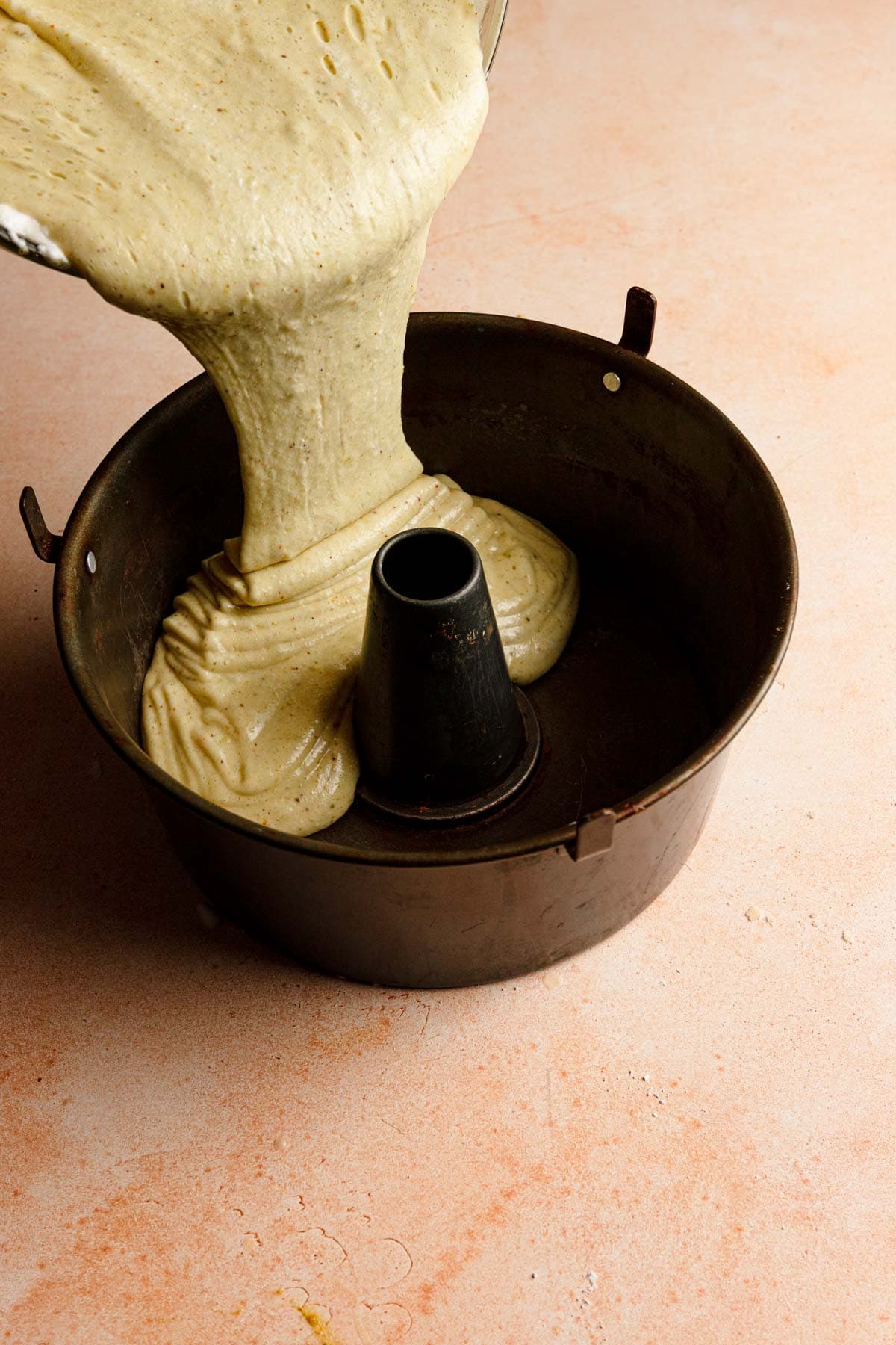 Pouring pistachio chiffon batter into a tube pan.