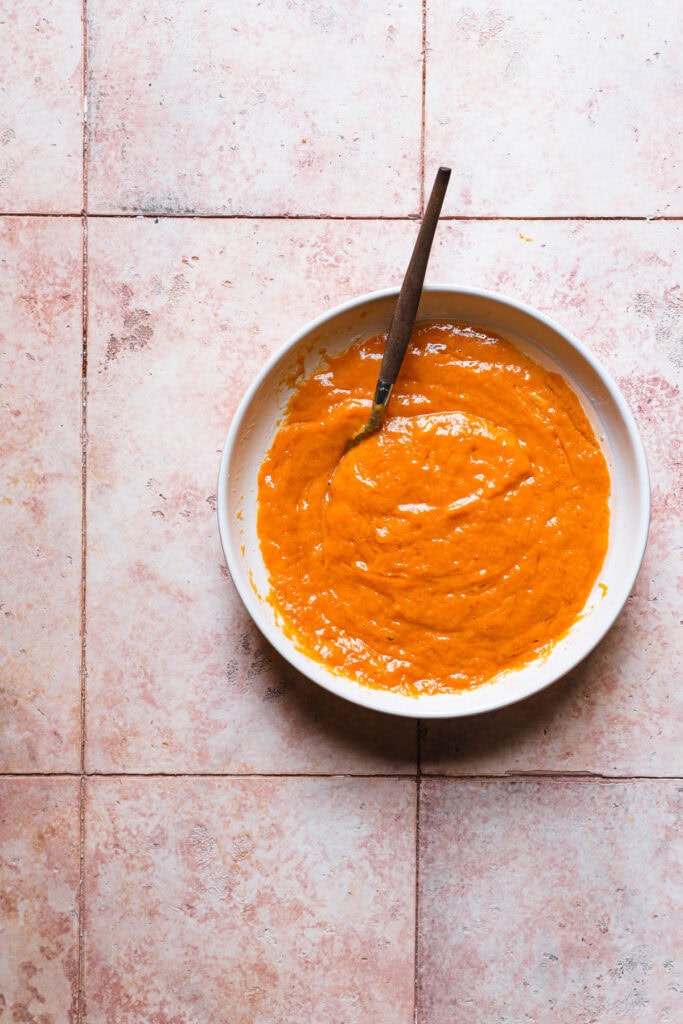 A bowl with eggs and pumpkin mixture with a fork.