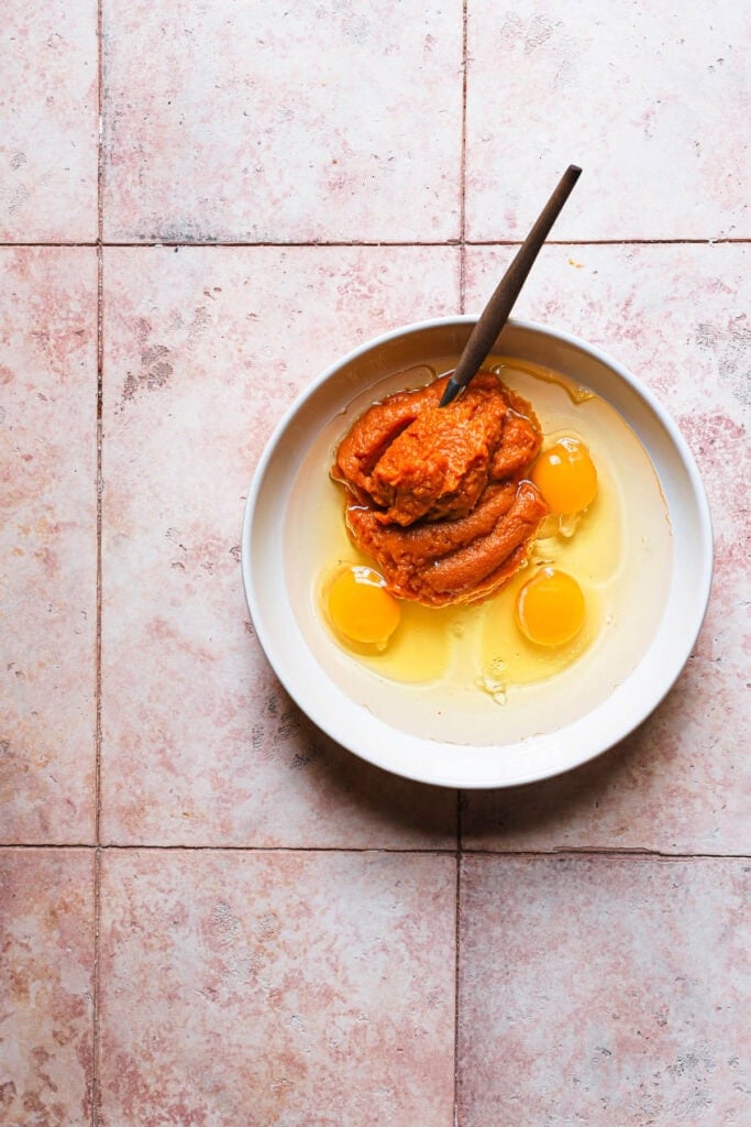 A bowl with eggs and pumpkin puree with a fork.