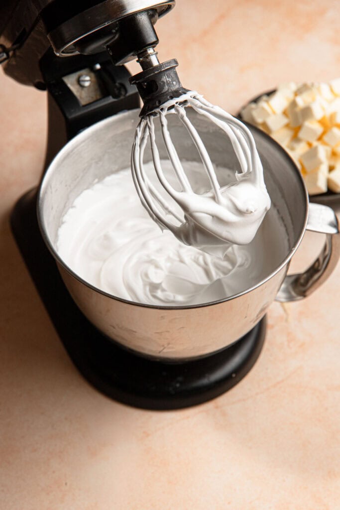A stand mixer with a bowl full of stiff meringue.