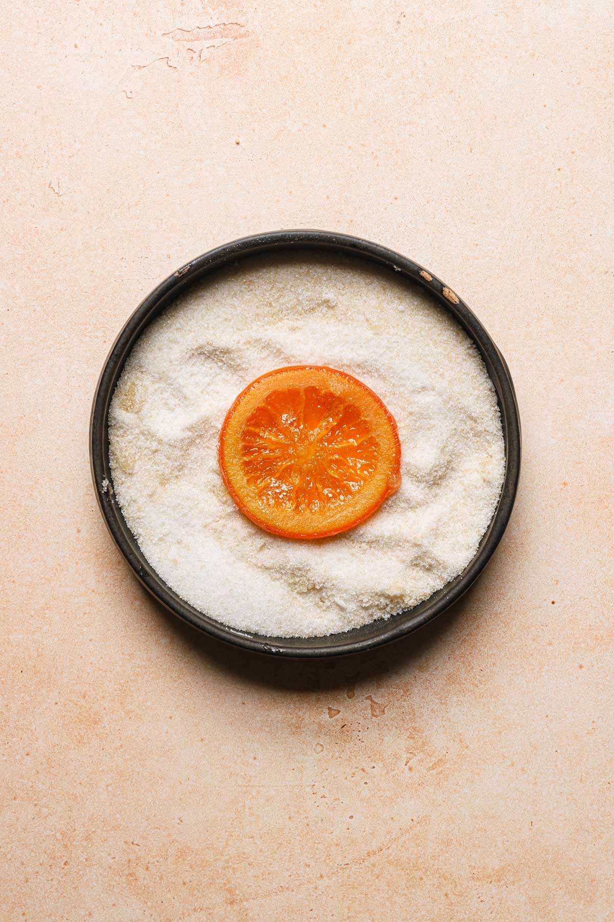 A bowl with sugar and candied orange slice.
