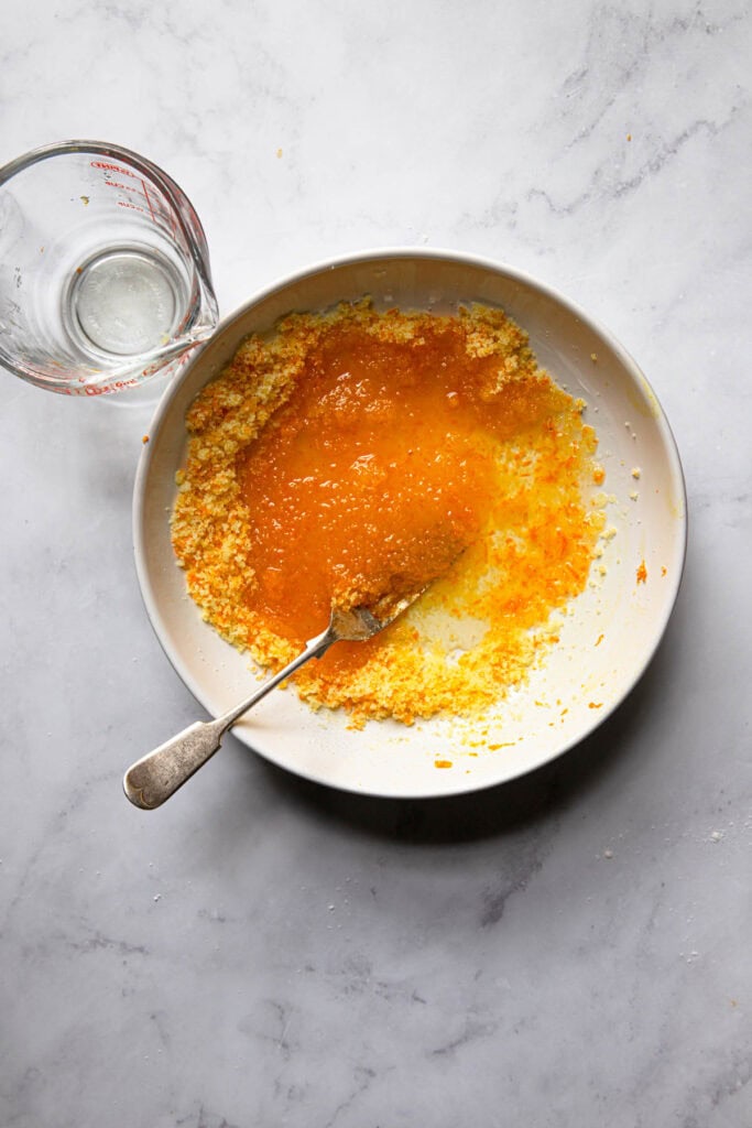A bowl with orange sugar, oil and a fork.