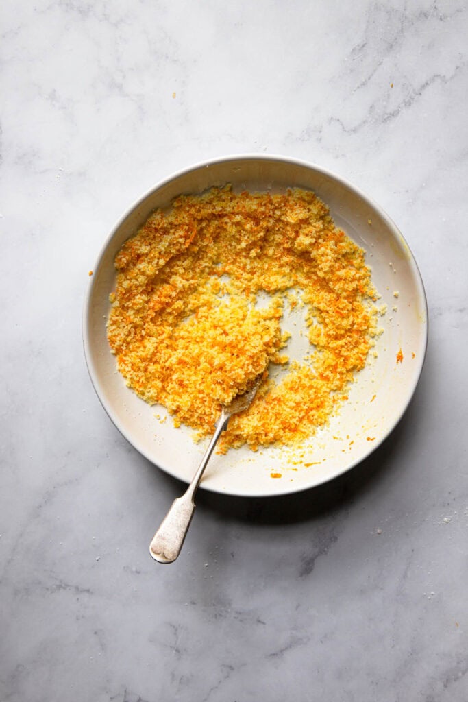 A bowl with orange sugar and a fork.