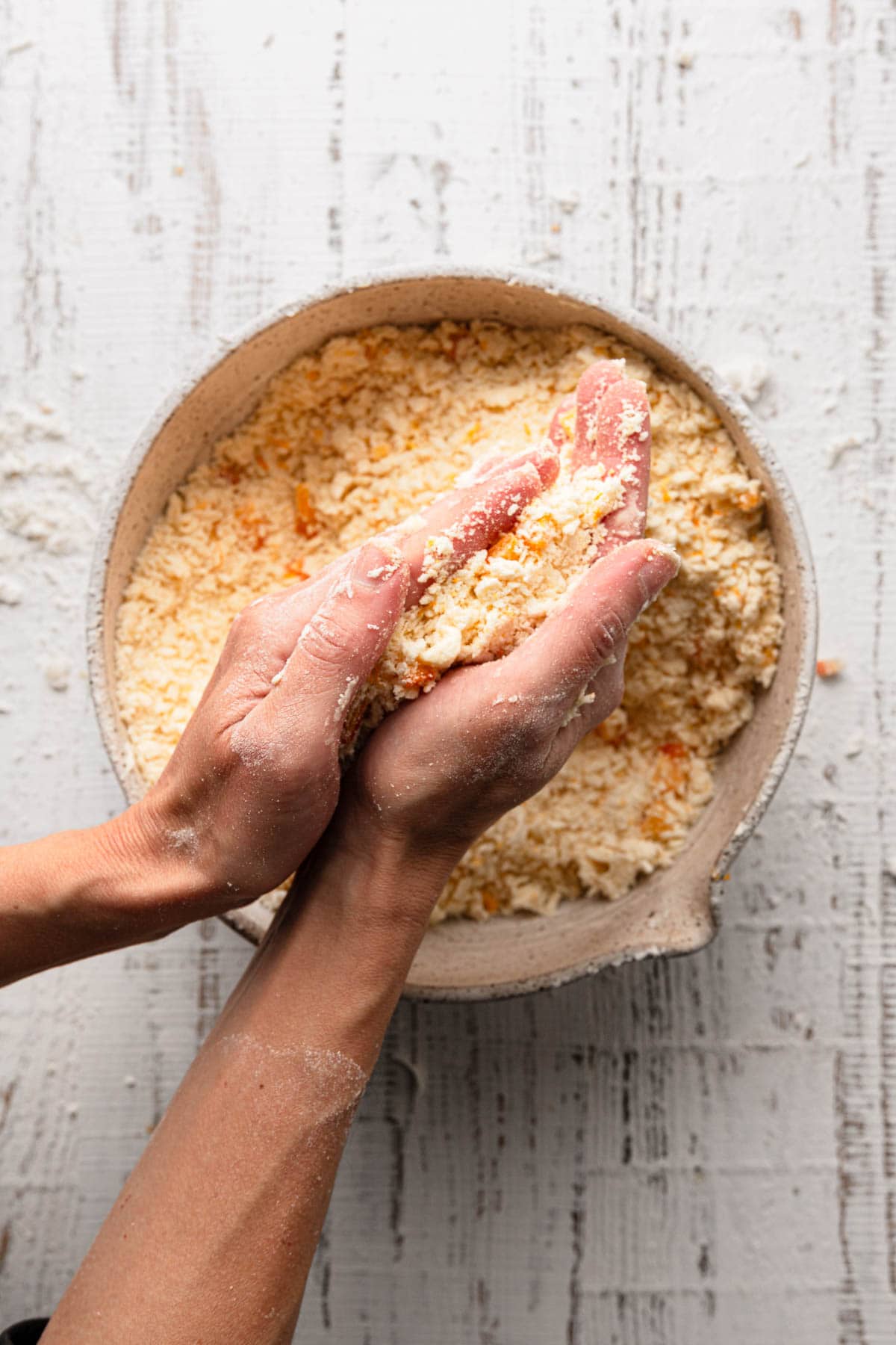 Hands rubbing butter into flour.