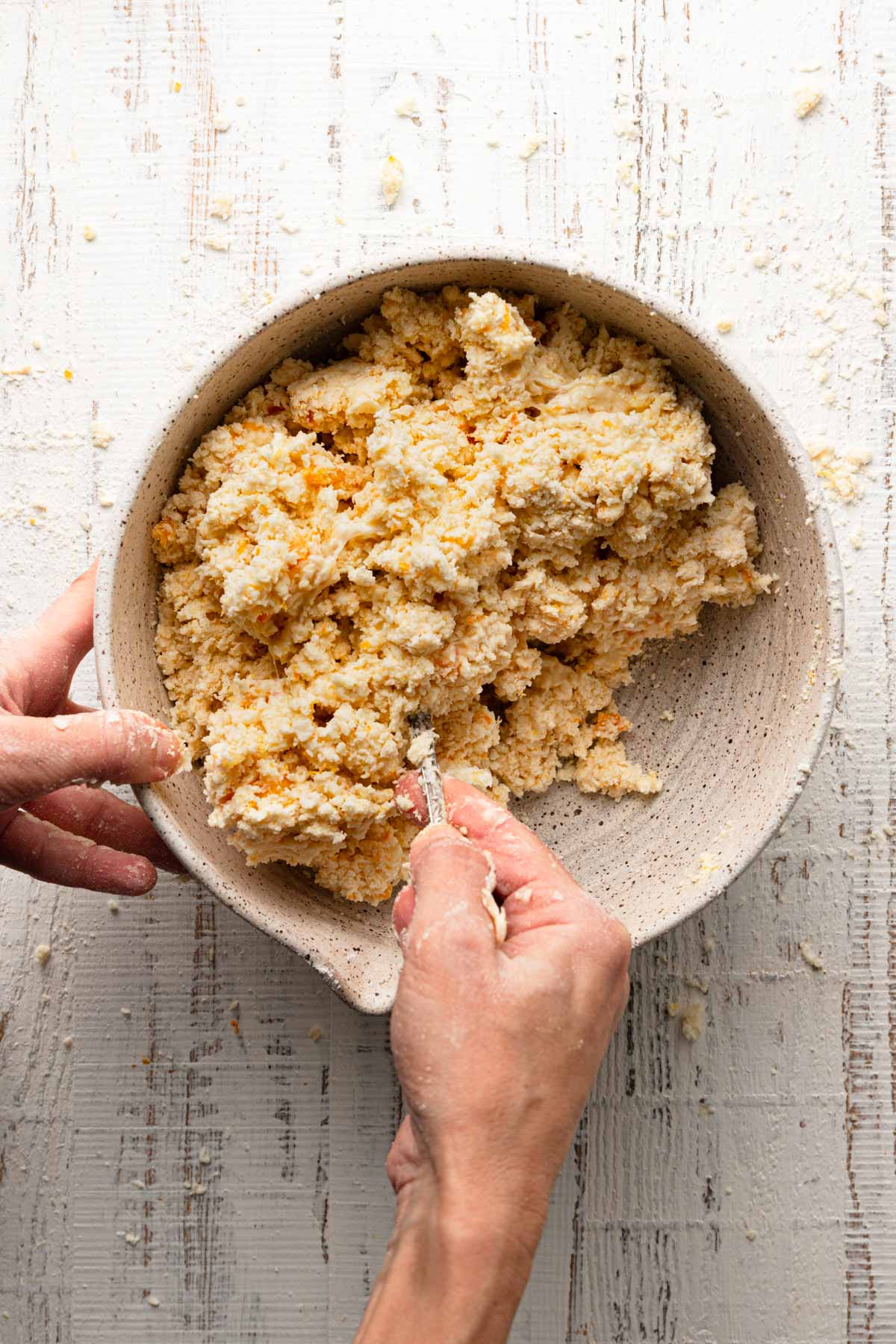 A hand mixing scones dough with a fork.