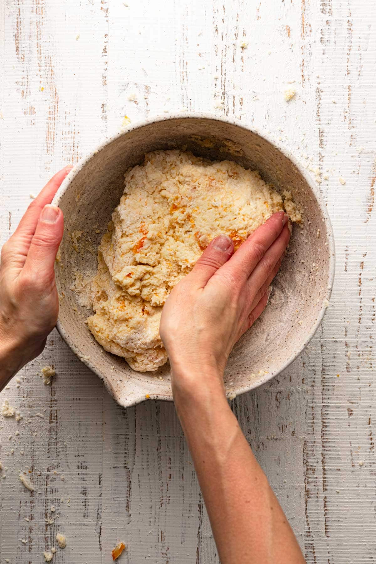 Hands pressing scones dough.