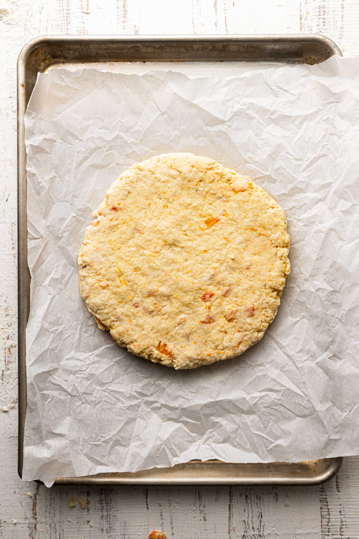 A large pan with parchment paper and a dough shaped into a circle.