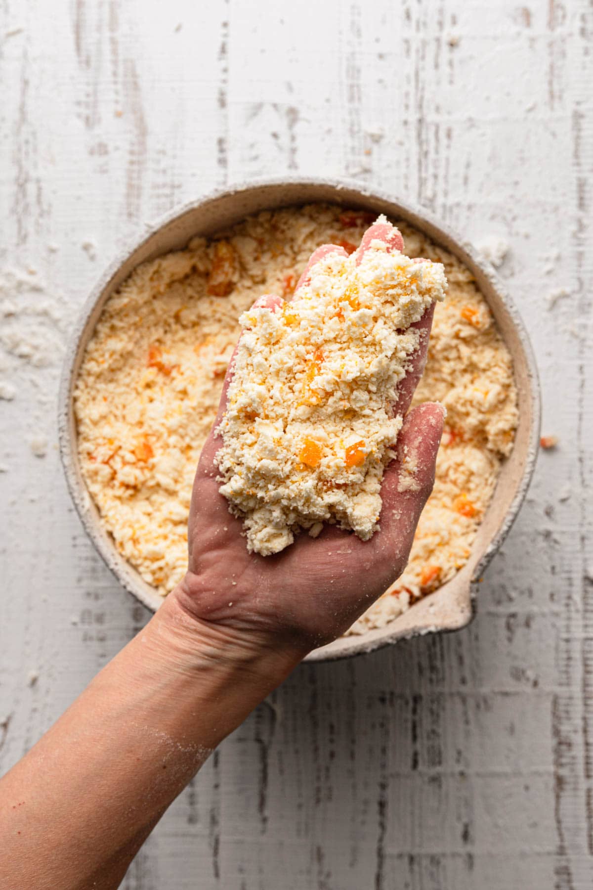 A hand holding flour butter mixture for making scones.