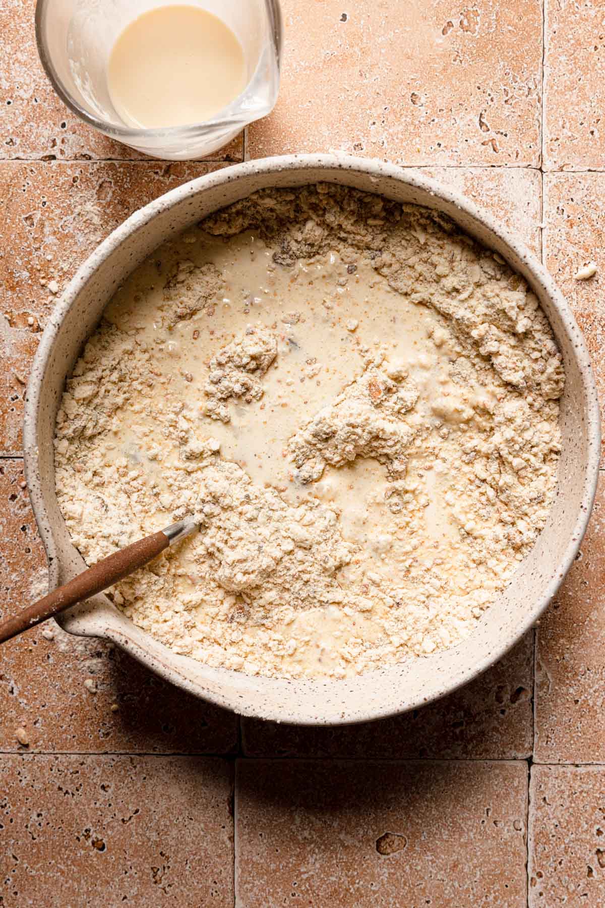 A bowl with flour mixture topped with liquids and a fork.