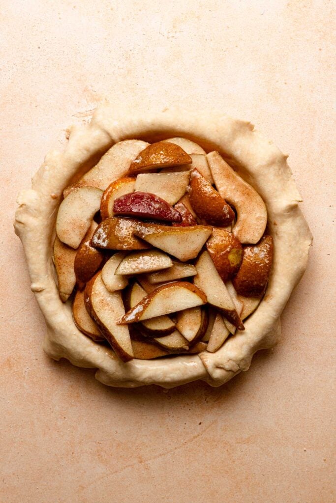 A pie shell filled with sliced pears filling.