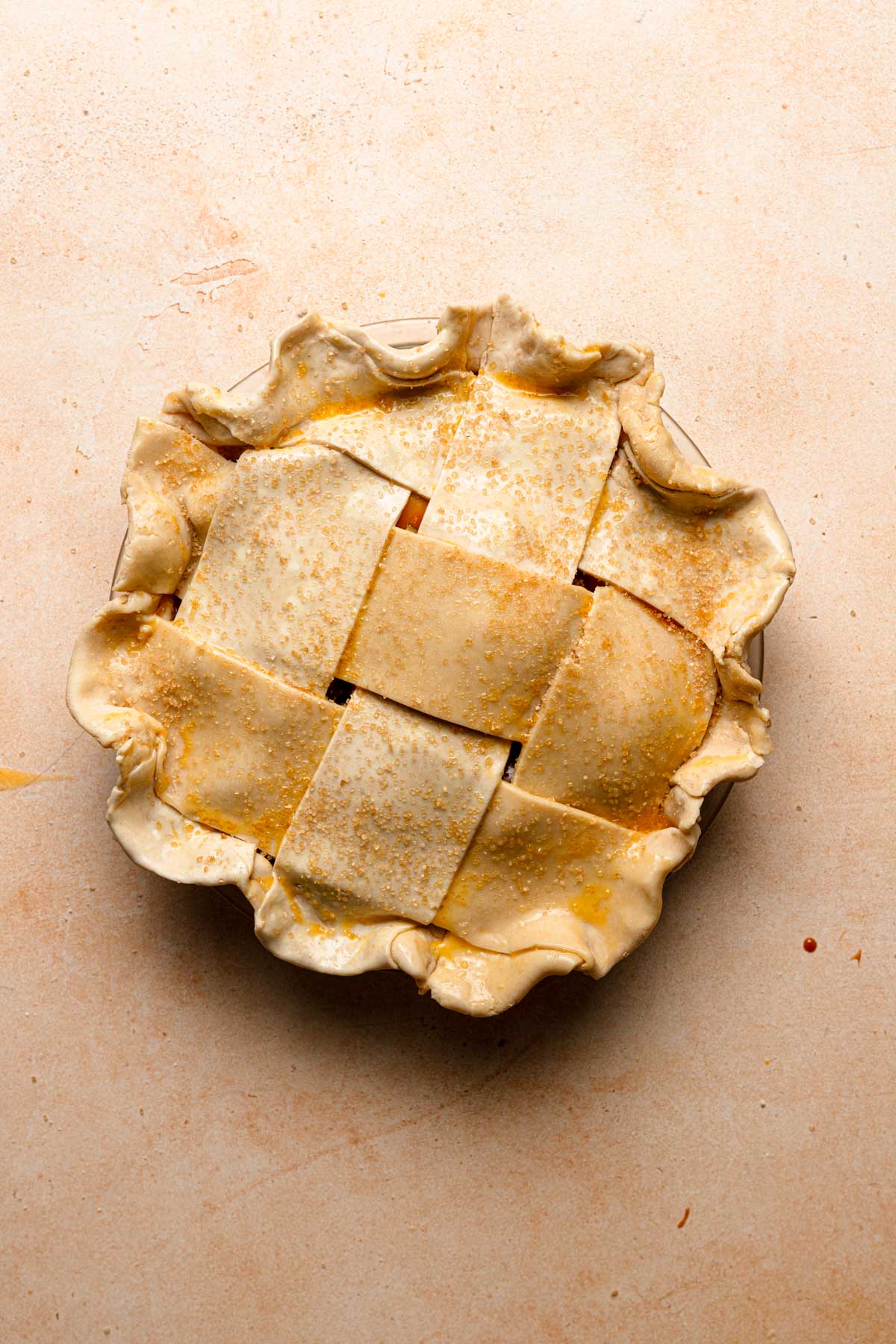 Unbaked pie topped with lattice decoration, and brushed with egg and turbinado sugar.