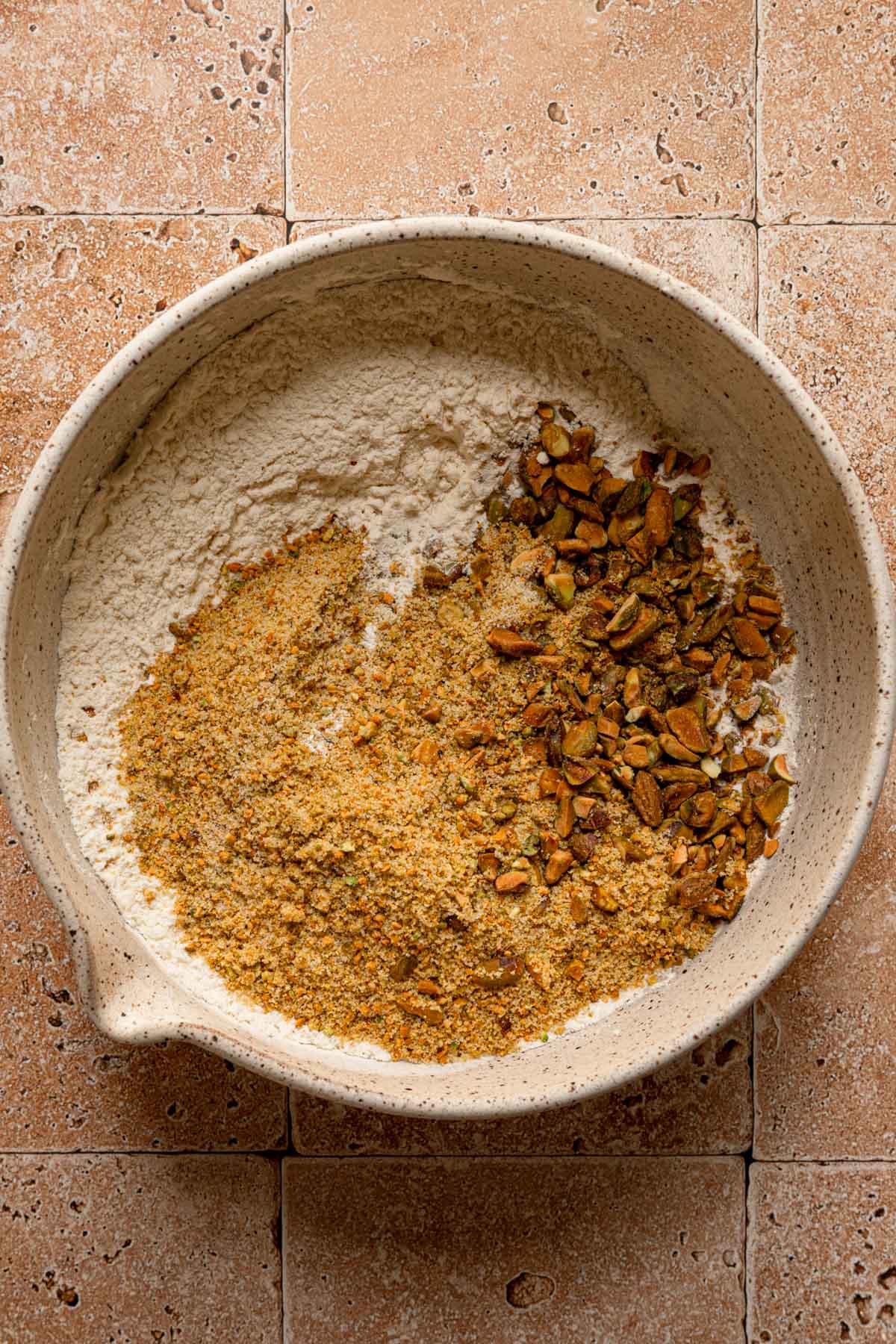A large bowl with flour and chopped pistachios.
