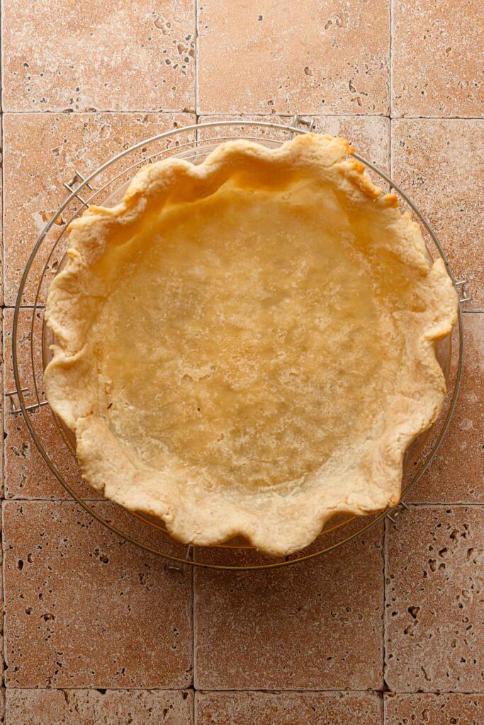 A par-baked pie crust over a cooling wrack.