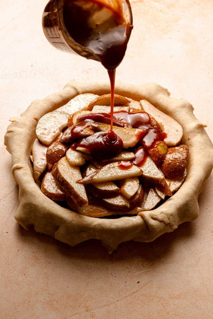 Pouring caramel over sliced pear filling.