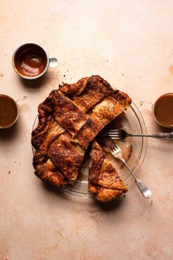 Sliced pie with forks, and coffee next to it.